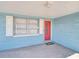 Cozy front porch featuring a vibrant red door, decorative welcome mat, and views of the well-maintained lawn at 3814 Sunray Dr, Holiday, FL 34691
