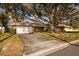 Brick home with a two-car garage and beautiful mature tree in the front yard with blue skies and clouds at 3960 13Th Ne Way, St Petersburg, FL 33703