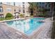 Bright and refreshing community pool with brick trim and lounge seating surrounded by lush landscaping and multi-story building at 4221 W Spruce St # 2205, Tampa, FL 33607