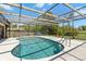Sparkling screened-in pool featuring a lounge chair and manicured landscaping at 5140 Kirkwood Ave, Spring Hill, FL 34608