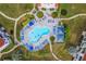 Overhead view of community pool with plenty of seating and shade umbrellas surrounded by lush green landscape at 6059 Bahia Del Mar Blvd # 141, St Petersburg, FL 33715