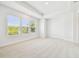A light-filled bedroom with large windows, neutral carpet, and tray ceiling at 6605 N Nebraska Ave # 28, Tampa, FL 33604