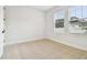 Small bedroom featuring a light colored patterned carpet, white walls, and bright sunlight through windows at 6605 N Nebraska Ave # 28, Tampa, FL 33604
