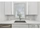 Bright kitchen sink with white cabinets, light backsplash, stainless faucet, and window at 6605 N Nebraska Ave # 28, Tampa, FL 33604