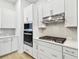 Close up view of a white kitchen with a gas cooktop and modern appliances at 6605 N Nebraska Ave # 28, Tampa, FL 33604