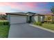 Charming single-story home with a two-car garage, well-maintained lawn, and inviting curb appeal under a colorful sky at 6727 Bar S Bar Trail, Zephyrhills, FL 33541