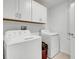 Functional laundry room with white cabinets, washer, dryer, and storage for laundry supplies and cleaning equipment at 6727 Bar S Bar Trail, Zephyrhills, FL 33541