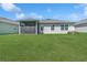 A well-kept lawn graces this backyard featuring a covered patio perfect for relaxation and entertaining at 8352 Greenway Ave, Wesley Chapel, FL 33544
