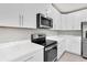 Modern kitchen with white cabinets, quartz countertops, and stainless steel appliances at 8352 Greenway Ave, Wesley Chapel, FL 33544