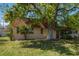 Exterior view of the home showing mature shade tree, lawn, and architectural style at 8445 Calais N, Pinellas Park, FL 33781