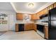 A compact kitchen featuring wood cabinets, an electric range, and black appliances at 8445 Calais N, Pinellas Park, FL 33781