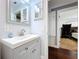 Well-lit bathroom vanity area with a gray cabinet, white sink, and modern fixtures; view into a bedroom at 910 Lakeside Dr, Largo, FL 33778