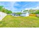 A fully fenced backyard features a large patio, lush lawn, and mature trees at 921 Woodland Dr, Palm Harbor, FL 34683