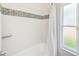 A bathroom showing decorative tile trim and a decorative shower curtain beside a bright window at 921 Woodland Dr, Palm Harbor, FL 34683