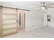 Bedroom featuring a glass sliding barn door, ceiling fan, and lots of natural light at 921 Woodland Dr, Palm Harbor, FL 34683