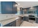 Modern kitchen features stainless steel appliances, marble countertops and blue cabinetry at 921 Woodland Dr, Palm Harbor, FL 34683