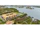 An aerial view of the building, tennis court, dock, and surrounding green landscape with water views at 12760 Indian Rocks Rd # 571, Largo, FL 33774