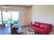 Bright living room featuring hardwood floors, sliding glass doors to the patio, and a red leather sofa at 10048 Cleghorn Dr, San Antonio, FL 33576