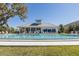 Community pool with sun loungers and blue umbrellas, featuring an adjacent outdoor clubhouse at 1010 Mango Ct, Oldsmar, FL 34677