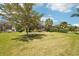Expansive backyard showcasing manicured lawn and mature trees and shrubs with screened patio at 10612 Glencorse Ter, Bradenton, FL 34211