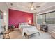 Elegant bedroom showcasing a magenta accent wall, a ceiling fan, and soft neutral carpet at 10612 Glencorse Ter, Bradenton, FL 34211