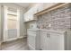 Bright laundry room with white cabinets, mosaic backsplash, and a stainless-steel sink at 11110 Swansea St, Riverview, FL 33578