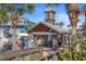 Charming John's Pass Village entrance featuring a directory sign, nestled among lush palm trees and blue skies at 12924 Gulf Blvd # 502, Madeira Beach, FL 33708