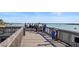 Scenic wooden pier with people enjoying waterfront views under a sunny sky in a fun and friendly neighborhood at 12924 Gulf Blvd # 502, Madeira Beach, FL 33708