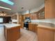 Spacious kitchen featuring wooden cabinets, tiled floors, a central island, and modern appliances at 131 E Saint Annes Cir, Apollo Beach, FL 33572