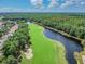 Aerial view showcasing a lush golf course winding alongside a serene river, surrounded by trees at 16323 Muirfield Dr, Odessa, FL 33556