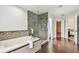 Luxurious bathroom featuring a soaking tub, glass-enclosed shower, and wood-look tile floors at 16323 Muirfield Dr, Odessa, FL 33556