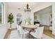 Elegant dining room with hardwood floors, white chairs, a chandelier, and a view of the adjacent kitchen area at 16323 Muirfield Dr, Odessa, FL 33556
