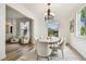 Bright dining room with hardwood floors, white chairs, a modern chandelier, and a view of the front yard at 16323 Muirfield Dr, Odessa, FL 33556