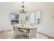 Dining area featuring modern lighting, wood table with seating, and a view of the neighborhood through large windows at 16323 Muirfield Dr, Odessa, FL 33556