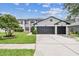 Beautiful two-story home with a well-manicured lawn and a three-car garage, with gray and black paint at 16323 Muirfield Dr, Odessa, FL 33556