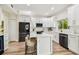Modern white kitchen with stainless appliances, light wood floors, and center island with bar stool seating at 16323 Muirfield Dr, Odessa, FL 33556
