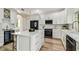 Modern white kitchen with quartz countertops, stainless steel appliances, a center island, and hardwood floors at 16323 Muirfield Dr, Odessa, FL 33556