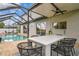 Outdoor dining area next to pool and screened in porch on the rear exterior of home at 16323 Muirfield Dr, Odessa, FL 33556