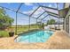 A screened pool with waterfall feature surrounded by brick pavers and views of an open field at 16323 Muirfield Dr, Odessa, FL 33556