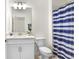 Well-lit bathroom with a single sink vanity, toilet, and a shower with a blue and white striped curtain at 17214 Star Banks St, Wimauma, FL 33598