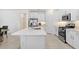Bright, all-white kitchen featuring a large island, stainless steel appliances, and modern finishes at 17214 Star Banks St, Wimauma, FL 33598