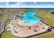 Aerial view of a large lagoon with sandy beach, lounge chairs, and water inflatables, surrounded by a residential community at 17214 Star Banks St, Wimauma, FL 33598