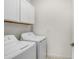 Bright laundry room features a stacked washer and dryer, plus ample storage with overhead white cabinets at 17214 Star Banks St, Wimauma, FL 33598