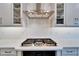 Close up of the kitchen cooktop with white tile backsplash, stainless steel hood, and quartz counters at 19611 Cypress Bridge Dr, Odessa, FL 33556