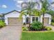 Elegant home featuring three-car garage, a beautiful lawn, and lush landscaping at 19611 Cypress Bridge Dr, Odessa, FL 33556