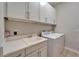 This laundry room features white cabinets, countertops, sink, and a modern washer and dryer at 19611 Cypress Bridge Dr, Odessa, FL 33556