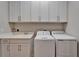 Bright laundry room featuring white cabinets, countertops, sink, and modern washer and dryer at 19611 Cypress Bridge Dr, Odessa, FL 33556