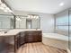 Lavish bathroom features a double vanity sink, large mirrors, a tub, and a glass-enclosed shower at 22119 Weeks Blvd, Land O Lakes, FL 34639