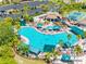 Aerial view of pool with lounge chairs, lush green trees, parking and tennis courts at 2618 Newcomb Ct # 12, Sun City Center, FL 33573