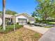 Charming home exterior with tropical trees, landscaping, garage, and driveway at 2618 Newcomb Ct # 12, Sun City Center, FL 33573